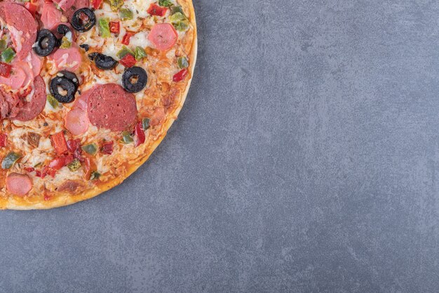 Pizza de pepperoni recién horneada sobre fondo gris.