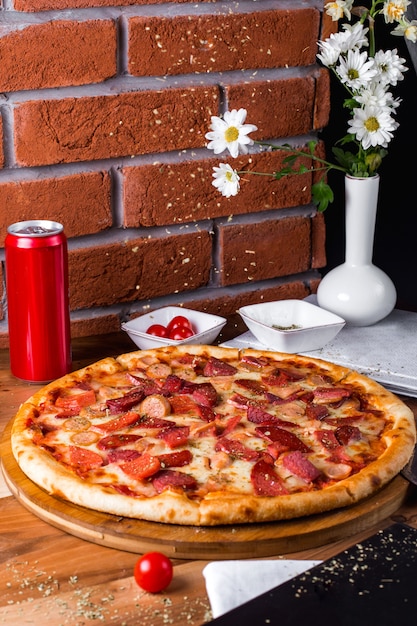 Pizza de pepperoni con tomate y lata de refresco sobre la mesa