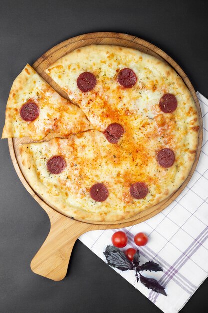 Pizza de pepperoni y tomates en la mesa