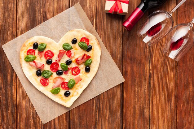 Pizza plana en forma de corazón con vino.