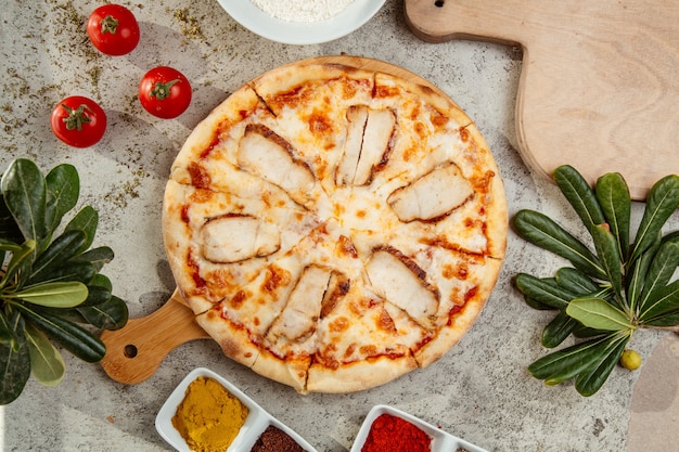 Foto gratuita pizza de pollo y unos tomates sobre la mesa