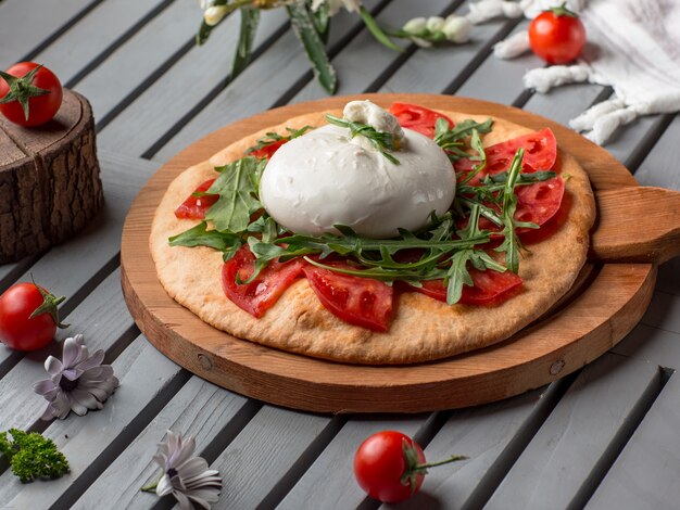 Pizza con rodajas de tomate, mozarella y hierbas.