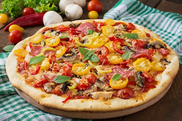 Foto gratuita pizza con salami, tomate, queso y champiñones.