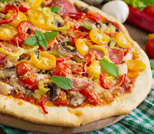 Pizza con salami, tomate, queso y champiñones.