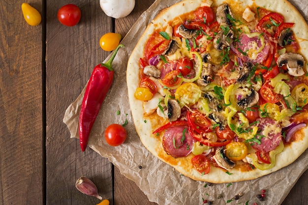 Pizza con salami, tomate, queso y champiñones.