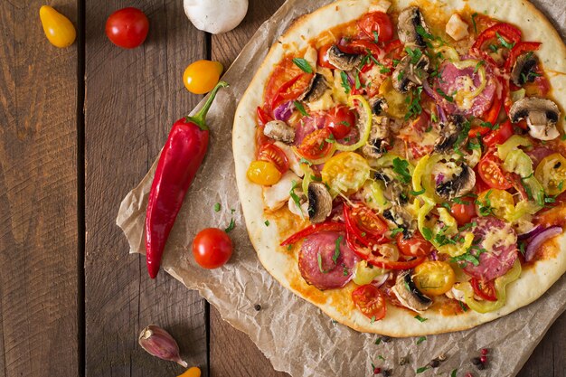 Pizza con salami, tomate, queso y champiñones.