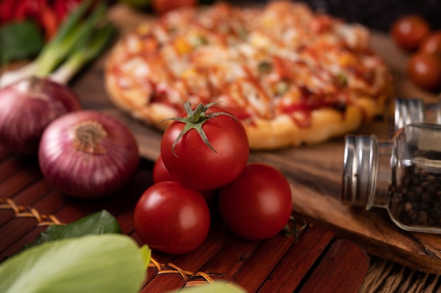 Pizza con salchicha, maíz, frijoles, camarones y tocino en una placa de madera