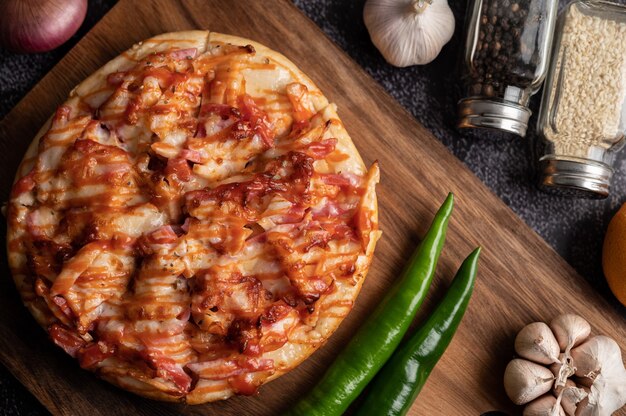 Pizza con salchicha, maíz, frijoles, camarones y tocino en una placa de madera