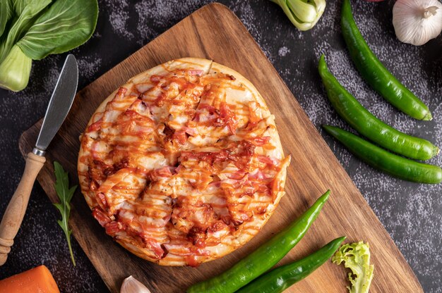 Pizza con salchicha, maíz, frijoles, camarones y tocino en una placa de madera