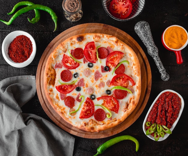 Pizza con salchichas tomates y aceitunas vista superior