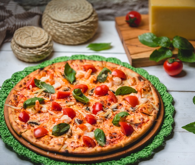 Pizza con tomate y albahaca sobre la mesa