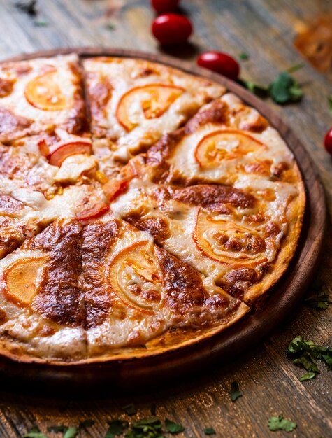 pizza con tomates en escritorio de madera