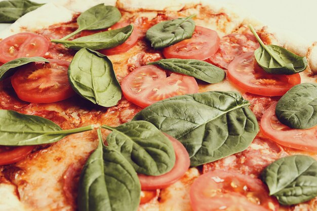 Pizza tradicional con rodajas de tomate y hojas de albahaca