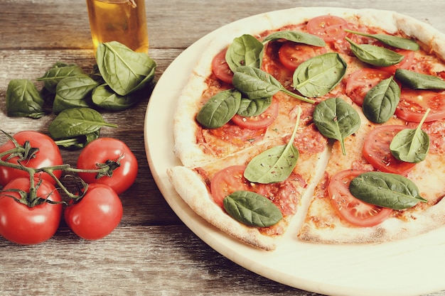 Pizza tradicional con rodajas de tomate y hojas de albahaca