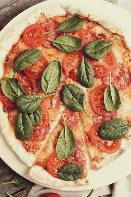 Pizza tradicional con rodajas de tomate y hojas de albahaca