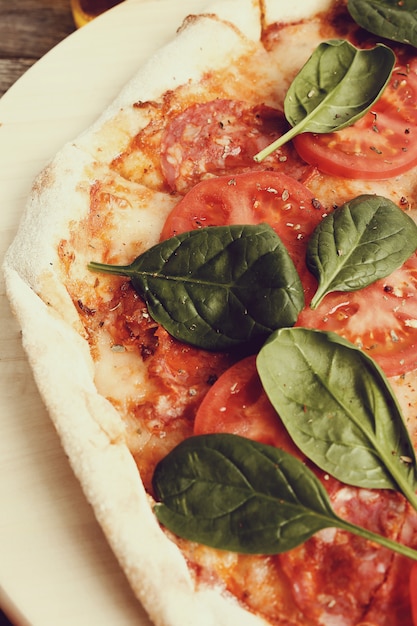 Pizza tradicional con rodajas de tomate y hojas de albahaca