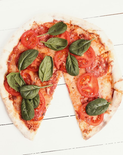 Pizza tradicional con rodajas de tomate y hojas de albahaca