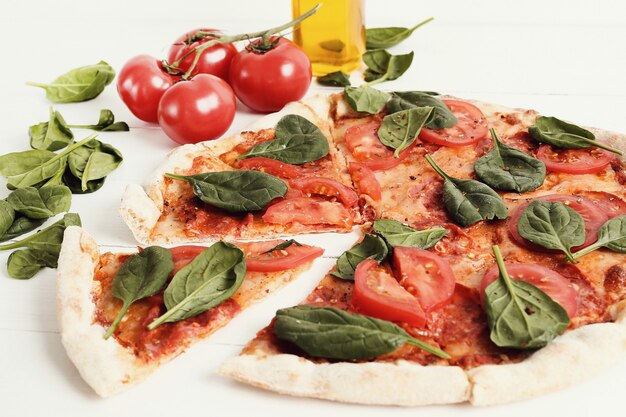 Pizza tradicional con rodajas de tomate y hojas de albahaca