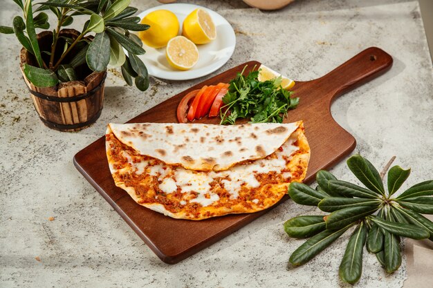 Pizza turca lahmajun con queso servido con perejil y limón