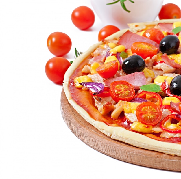 Pizza con verduras, pollo, jamón y aceitunas aislados en blanco