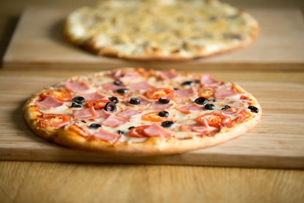 Pizzas italianas en tableros de madera en mesa de restaurante, concepto de pizzería