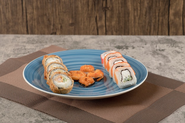 Placa azul de varios rollos de sushi sobre mesa de mármol