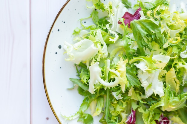 Foto gratuita placa de cerámica blanca con ensalada fresca sobre superficie de madera