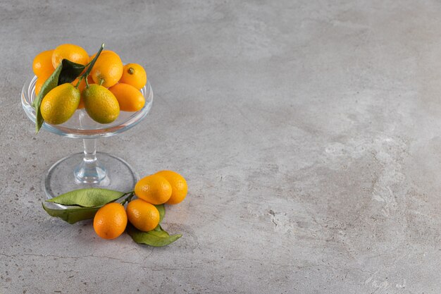 Placa de cristal de kumquats jugosos frescos sobre fondo de piedra.