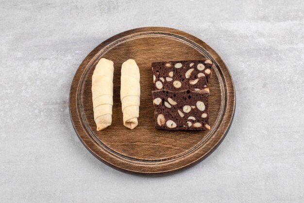 Placa de madera de dulces tradicionales mutaki y galletas de cacao en la mesa de piedra.