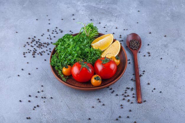 Placa de madera de verduras, tomates y limón sobre la superficie de piedra.