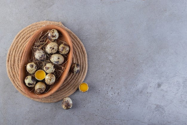 Una placa marrón llena de huevos de codorniz crudos colocados sobre la mesa de piedra.