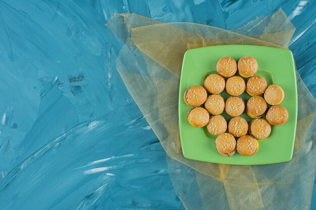 Una placa verde con hamburguesas gomitas de gelatina sobre una superficie azul