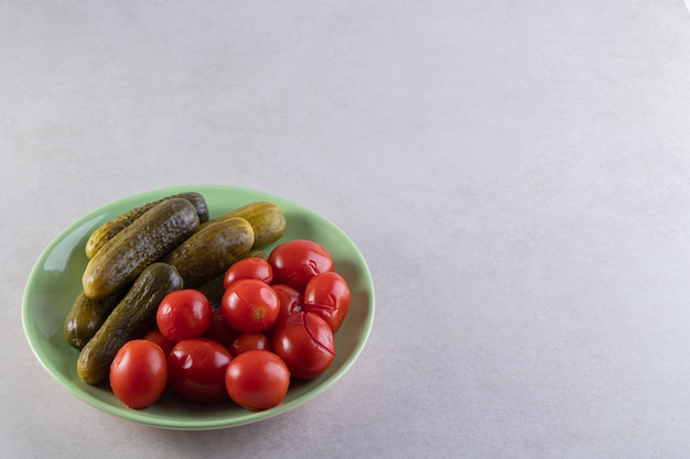 Foto gratuita placa verde de pepinos y tomates encurtidos en mesa de piedra.