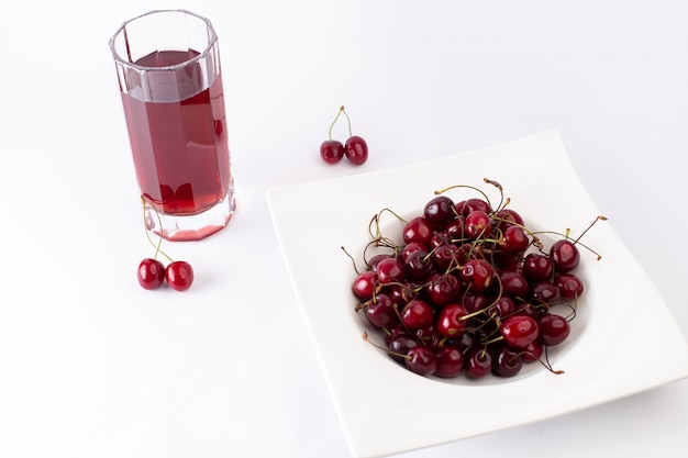 Placa de vista frontal con cerezas agrias y suaves junto con jugo de cereza en blanco