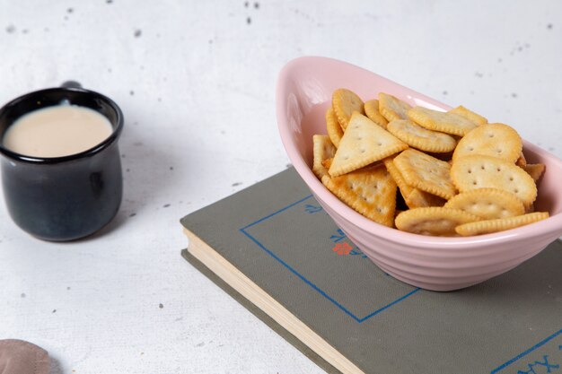 Placa de vista frontal rosa con galletas y patatas fritas junto con leche en gris