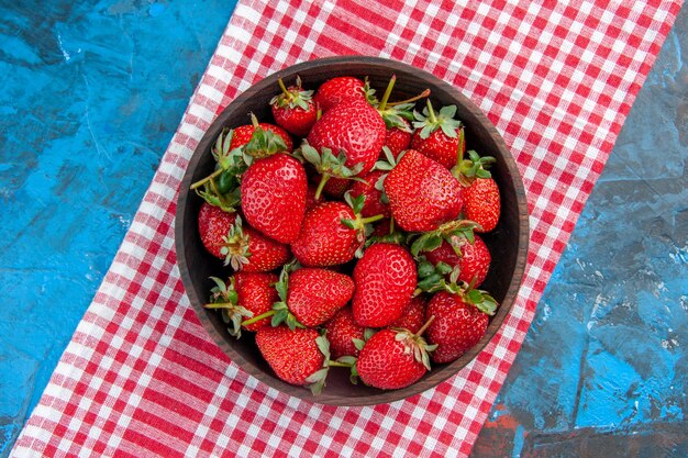 Placa de vista superior con fresas frescas frutas maduras sabrosas sobre fondo azul.