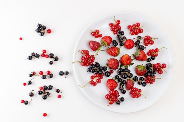 Placa de vista superior con fresas frescas y suaves con bluberries y arándanos sobre el fondo blanco color baya de fruta fresca y suave
