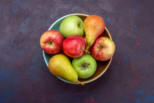 Placa de vista superior con frutas peras y manzanas en la superficie oscura