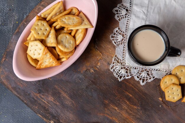 Placa de vista superior con galletas junto con una taza de leche en el fondo gris galleta crujiente