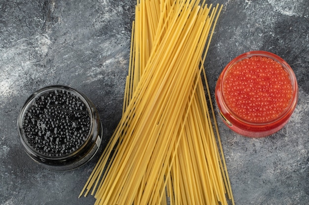 Foto gratuita placas de vidrio llenas de caviar rojo y negro sobre una mesa de mármol.