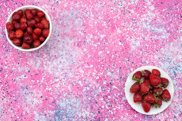 Placas de vista superior con fresas suaves y frescas sobre el fondo rosa