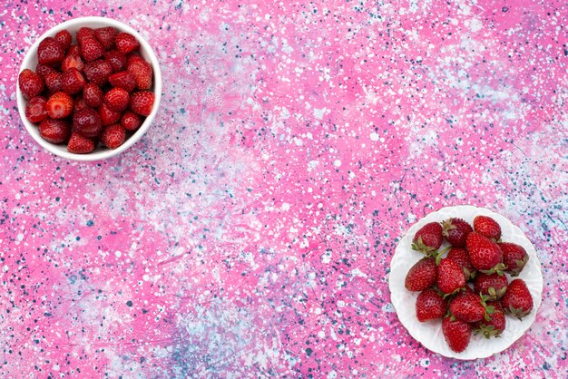 Placas de vista superior con fresas suaves y frescas sobre el fondo rosa