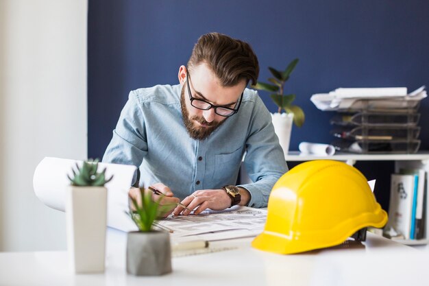 Plan de dibujo atractivo ingeniero masculino en plano en el lugar de trabajo