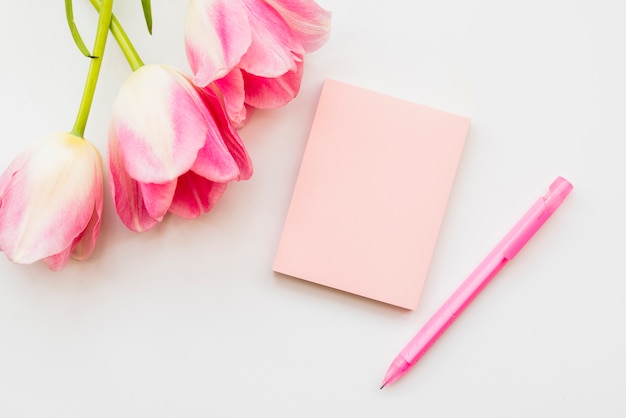 Foto gratuita plana puesta con ramo de flores y cuaderno con bolígrafo.