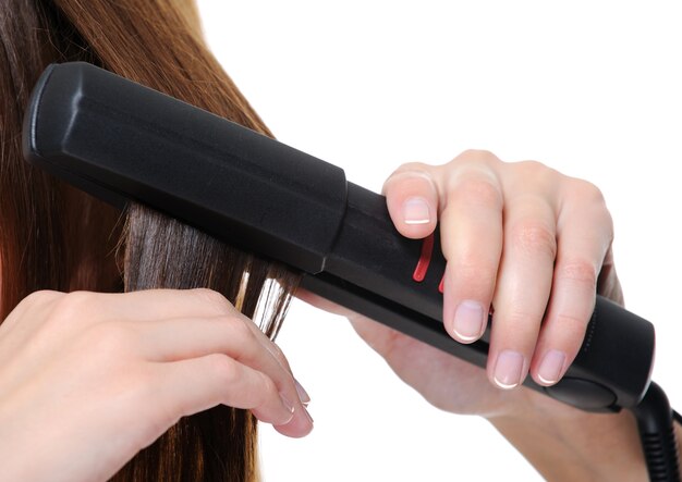 Plancha negra de primer plano aplicando sobre cabello morena femenina