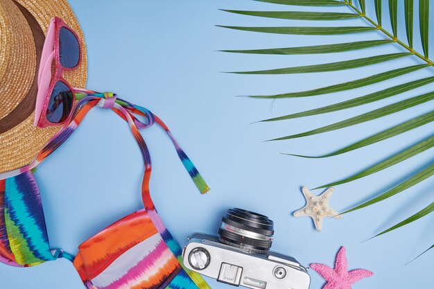 Planificación del viaje, viaje y viaje. Accesorios de viaje laicos planos sobre fondo azul con bikini, cámara, sombrero, gafas de sol. Concepto de vista superior, viajes o vacaciones. Fondo de verano.