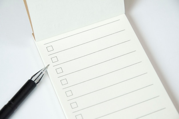 Planificador de lista en blanco para hacer con lista de verificación y lápiz negro sobre fondo blanco, de cerca