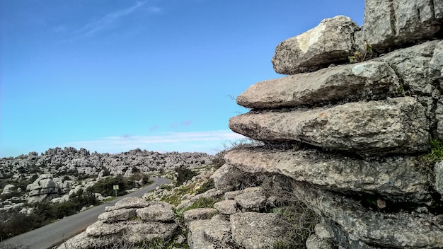 Plano amplio de capas de rocas y un cielo claro y brillante a lo largo de una carretera de asfalto suave