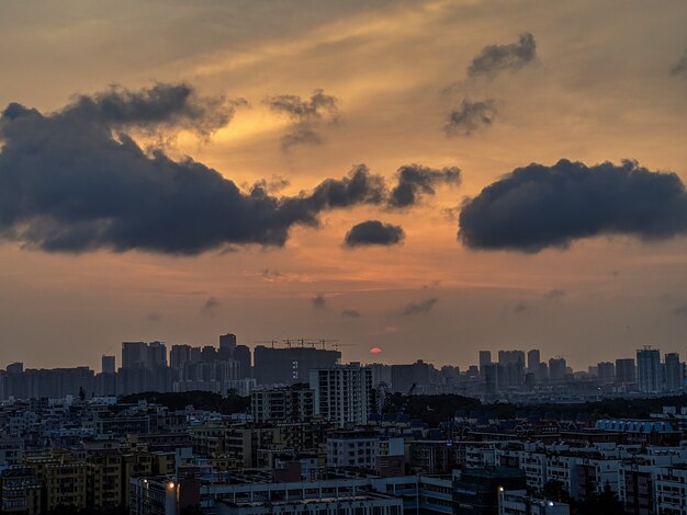 Plano amplio de una ciudad moderna y concurrida con nubes oscuras y cielo naranja