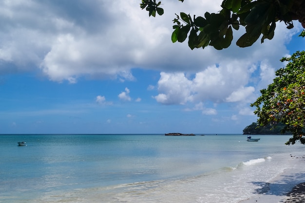 Plano amplio de una hermosa playa de arena con un nublado cielo azul de fondo